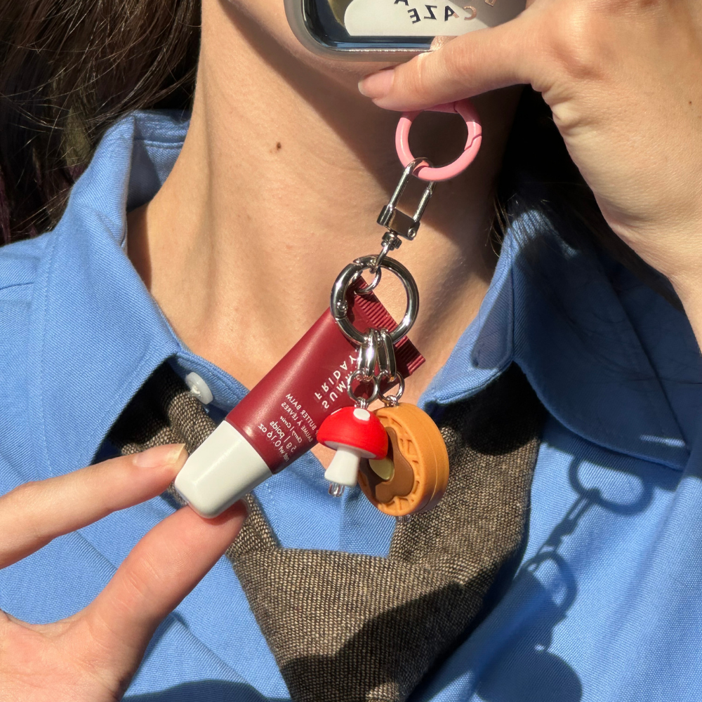 Red and white toadstool mushroom phone charm clipped near a collar, Build A Caze.