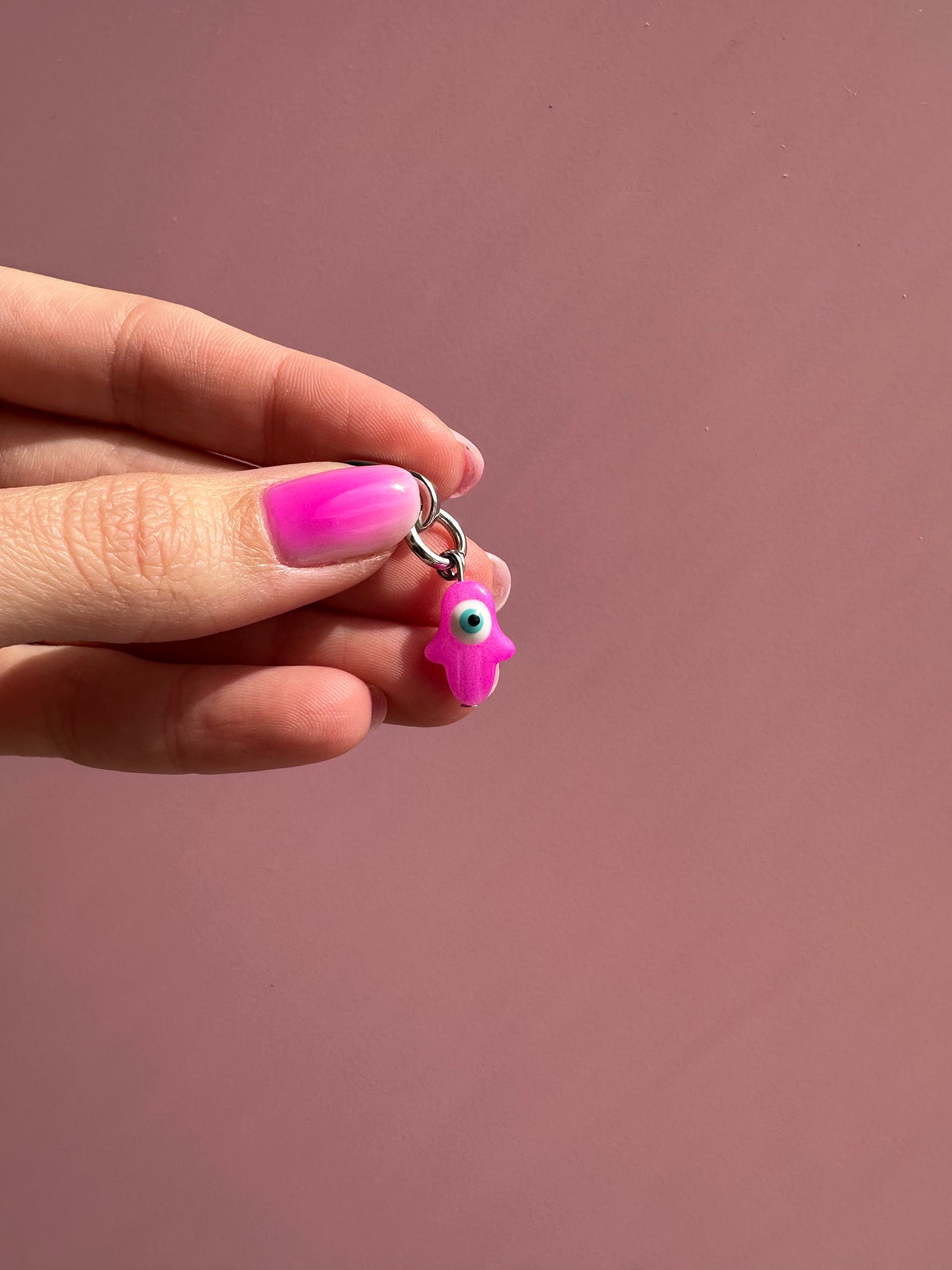 Hot pink evil eye phone charm featuring a vibrant protective nazar bead, trendy Y2K aesthetic mobile accessory and decorative tech strap by Build a Caze.