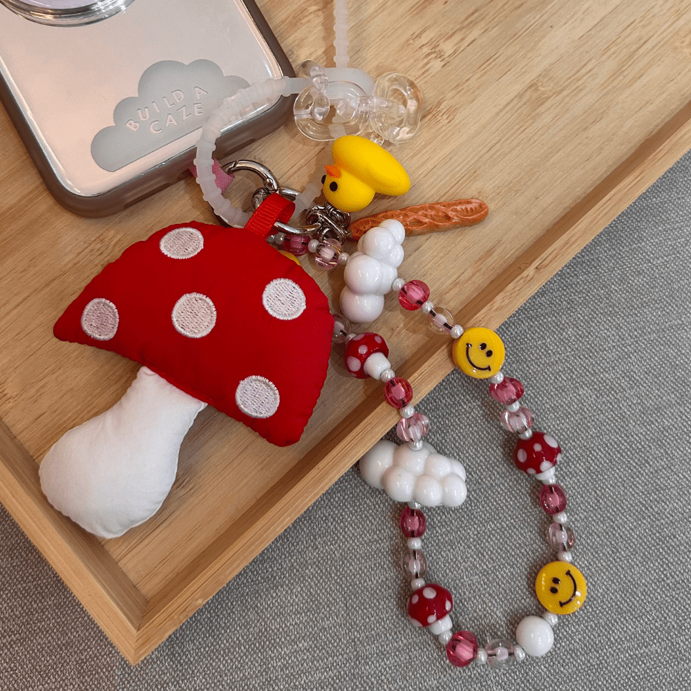 Baguette-shaped phone charm shown with a mushroom charm and a beaded phone strap, Build A Caze.