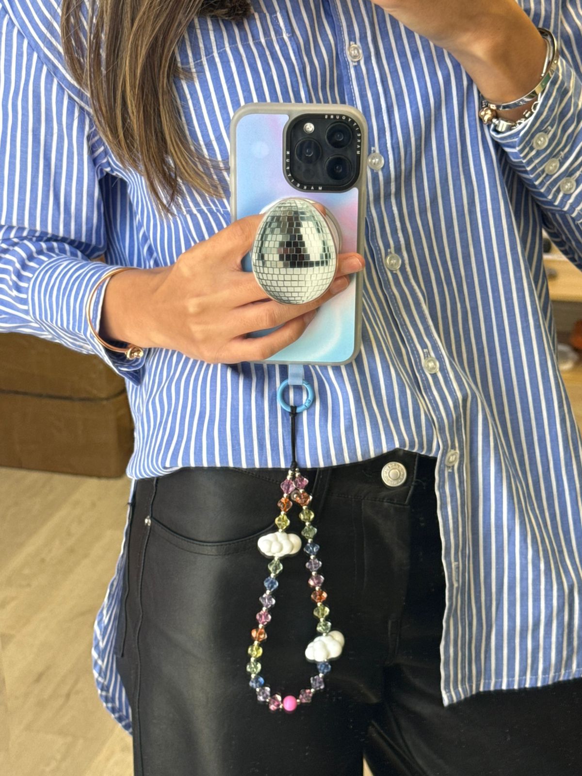 Beaded phone wrist strap featuring translucent rainbow beads and white cloud charms on a black cord lanyard, a cute and colorful mobile phone accessory.