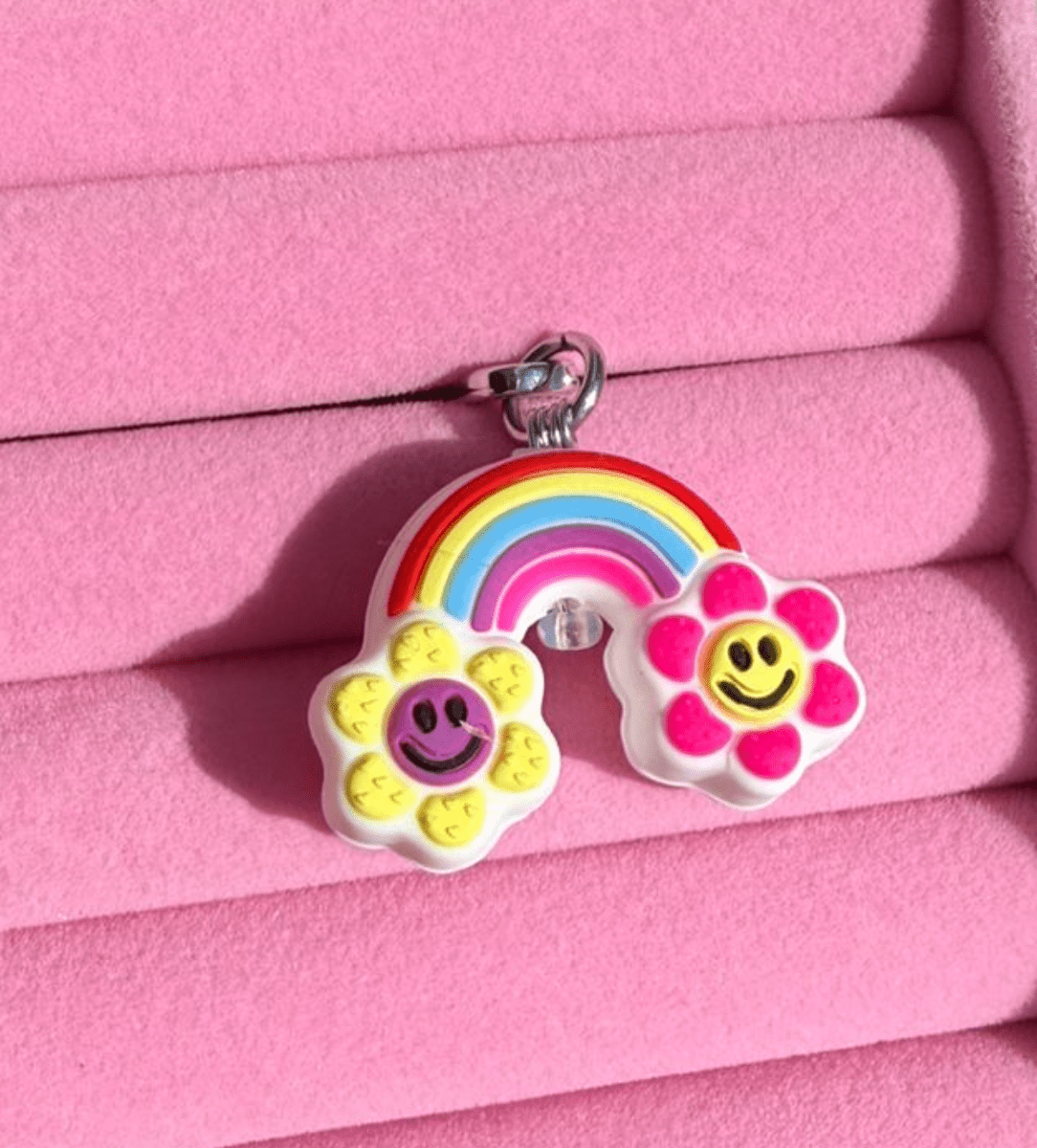 Pastel rainbow phone charm with two smiley flower clouds on each end, Build A Caze.