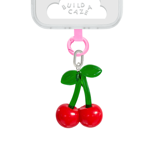 Vibrant red cherry phone charm with green leaf detail, oversized XL fruit-themed mobile accessory for Y2K aesthetic phone cases and trendy mirror selfies by Build a Caze.