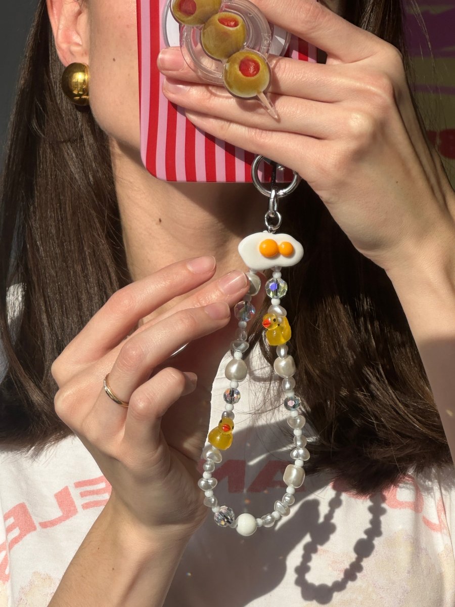 Cute sunny-side-up fried egg phone charm with a double yolk design, playful food-themed mobile accessory and Y2K aesthetic tech decoration by Build a Caze.