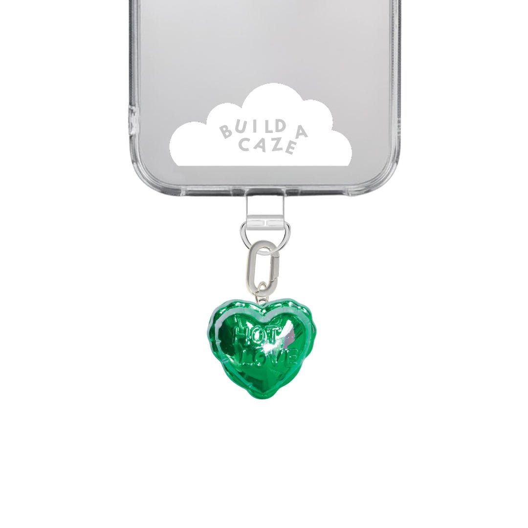 Green heart-shaped balloon phone charm with a "Hot Love" design, quirky Y2K aesthetic mobile accessory and decorative tech strap for phone cases by Build a Caze.