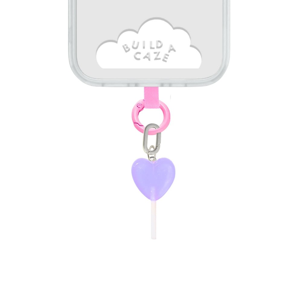 Cute heart-shaped lilac lollipop phone charm with a sweet candy aesthetic, trendy pink Y2K mobile accessory and decorative tech strap by Build a Caze.