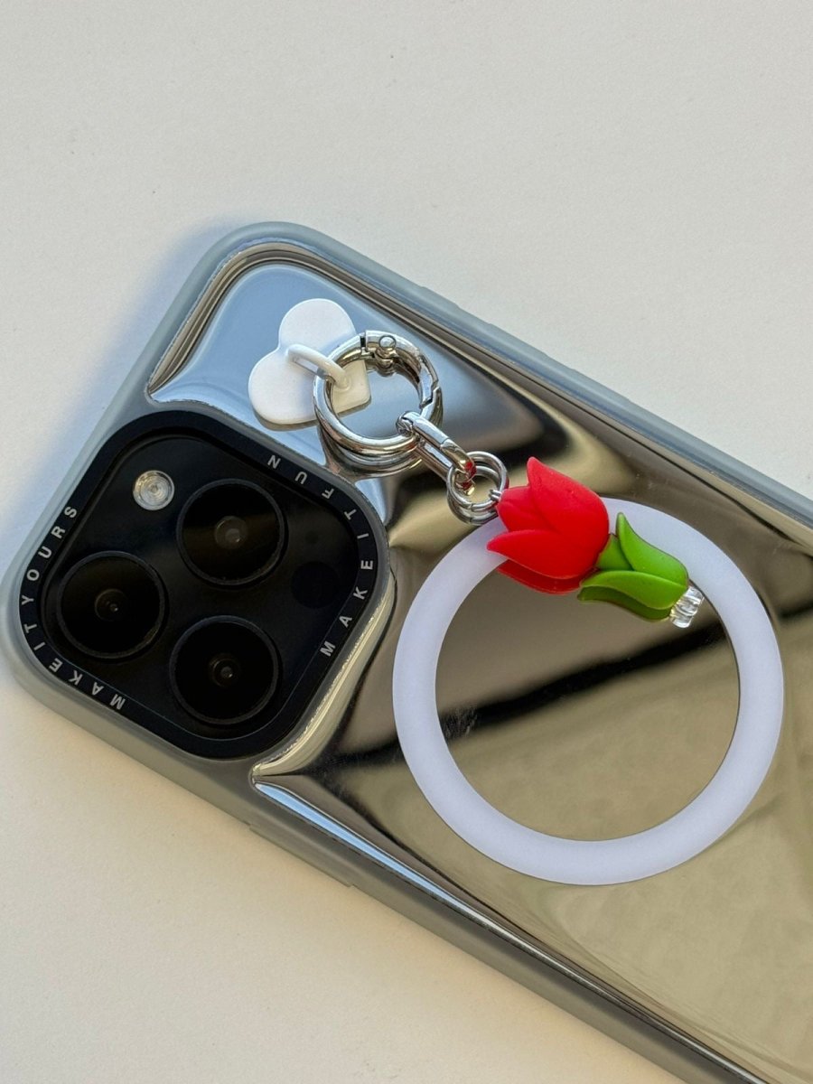 Red tulip flower phone charm dangling from a silver mirror phone case, Build A Caze.