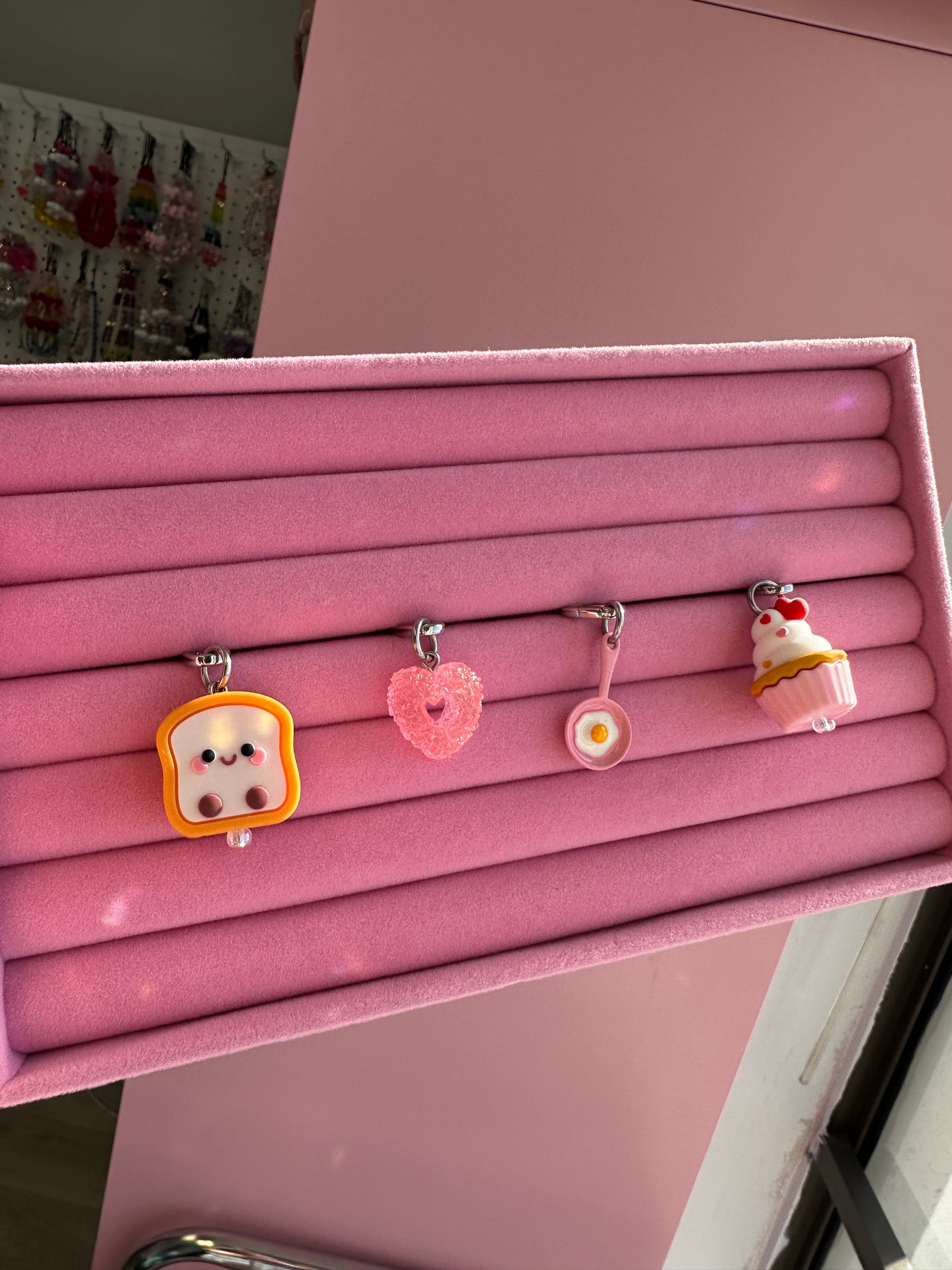Pink Sunny Side Up Charmie displayed on a pink stand alongside heart, cupcake and toast charmies Build A Caze