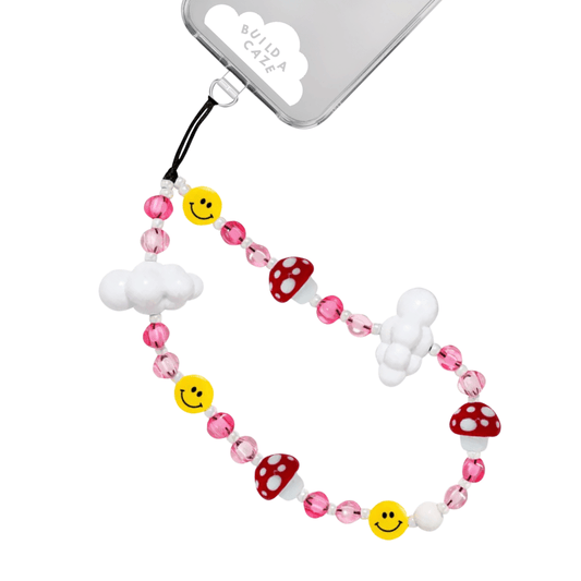 Beaded phone wrist strap featuring pink, red, and yellow mushroom and smiley face charms with white cloud beads on a black cord lanyard, an aesthetic phone strap and mobile phone accessory.